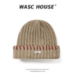 custom khaki soft wool blend chunky vertical rib skull cap, wide fold cuff with even spaced red contrast hand stitching, small white rectangular side tag minimal street winter hat