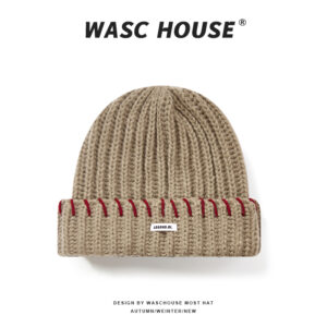 custom khaki soft wool blend chunky vertical rib skull cap, wide fold cuff with even spaced red contrast hand stitching, small white rectangular side tag minimal street winter hat