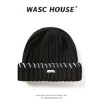 custom khaki soft wool blend chunky vertical rib skull cap, wide fold cuff with even spaced red contrast hand stitching, small white rectangular side tag minimal street winter hat